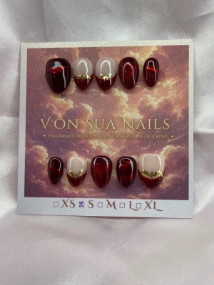BloodMoon (S);ExtraShortAlmond  - Unika handgjorda press-on naglar i vinrött med glansig finish och guldfärgade stjärndetaljer. Några naglar har nude bas med vinröd handmålad Cateye French . Formen är extra kort almond. Perfekt för dig som vill ha en lyxig och trendig look.S: 15 mm, 11,5 mm, 12 mm, 11 mm, 9 mm 