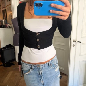 Svart kort kofta - Jättenice kort kofta/bolero med tre stora knappar framtill. Väldig urringning och passar perfekt till hösten att ha över en annan topp