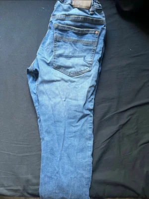 Blå jeans från Blue Ridge - Snygga blå jeans från Blue Ridge med klassisk femficksdesign och raka ben. Jeansen har en ljus tvätt och är tillverkade i mjukt denimtyg med kontrastsömmar. Perfekta för en avslappnad och trendig look.