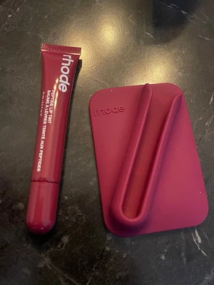 Rhode Peptide Lip Tint i bärig nyans - Säljer ett Rhode Peptide Lip Tint i en snygg bärig röd-lila nyans. Kommer i en smidig tub med vit text och tillhörande matchande hållare i silikon som enkelt fästs på mobilen. Perfekt för dig som vill ha återfuktade och lätt färgade läppar.