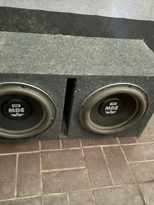 Dubbel baslåda med MDS subwoofers - Säljer en grå, rektangulär baslåda med två kraftfulla MDS subwoofers. Lådan är klädd i filtmaterial och har en port i mitten för bättre ljudåtergivning. Perfekt för dig som vill ha extra tryck i bilen.     Finns i svenljunga 