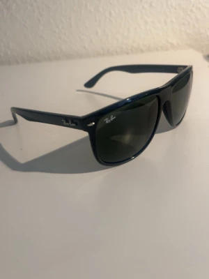 Svarta RayBan boyfriend - Snygga svarta solglasögon från Ray-Ban med klassisk boyfriend -form. Bågarna är i blank svart plast och glasen är mörka. Perfekta för soliga dagar och ger en tidlös look.