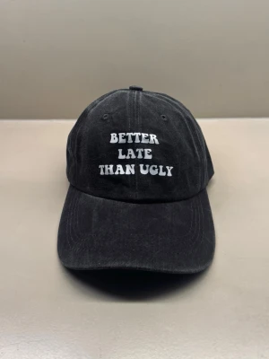 Better Late Than Ugly-keps – Vintage Washed Dad Cap | Humor | Unisex - Vintage-washed keps med vit text “BETTER LATE THAN UGLY” framtill.  Rolig och lättburen statement-keps med klassisk dad cap-look. Passar både till vardags och som present till någon med humor 😄  • Vintage-washed finish • Vit text framtill • Böjd skärm • Justerbar baktill • Unisex • Oanvänd / mycket fint skick