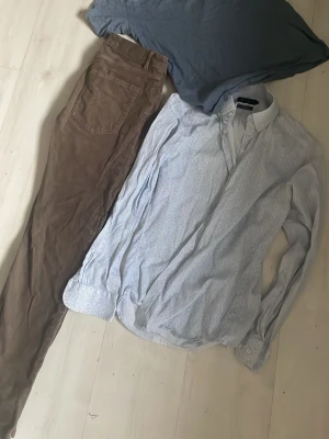 Riley  skjorta med diskret mönster - Snygg ljusblå skjorta med subtilt mönster och klassisk krage. Skjortan har långa ärmar och knappar framtill. Perfekt för dig som vill ha en stilren men ändå unik look.  Bruna Manchester jeans i 30.30 samt HM T-shirt