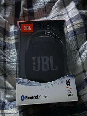 JBL Clip 4 trådlös högtalare svart - Smidig och portabel JBL Clip 4 Bluetooth-högtalare i svart. Utrustad med karbinhake för enkel upphängning, robust tygmaterial och gummerad baksida. Ger upp till 10 timmars speltid och har version 5.1 Bluetooth. Perfekt för att ta med överallt.