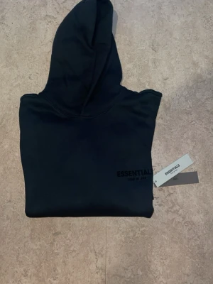 Essential fear of god hoodie  - Svart hoodie från Essentials Fear of God helt äkta och är verified med stor logga på ryggen och mindre logga framtill. Klassisk passform med luvan och väldigt varm har även och helt ny med plasticbagen fick den i present men passar inte mig ny pris ligger på 2300kr. (Priset kan diskuteras såklart)