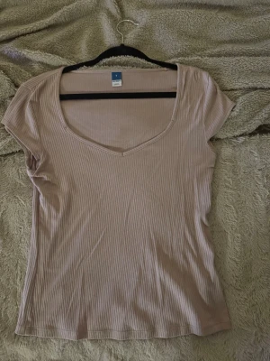 Beige topp  - Säljer en beige ribbad topp med v-ringning och korta ärmar. Endast använt vid ett tillfälle 