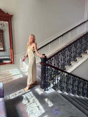 Ljusgul långklänning - Elegant ljusgul långklänning. Klänningen har en mjuk, följsam passform och är tillverkad i ett glansigt material som ger en lyxig känsla. Perfekt för sommarens alla tillfällen.
