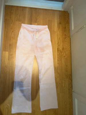 Ljusrosa mjukisbyxor med dragsko - Säljer ett par ljusrosa mjukisbyxor med raka ben och resårmidja med dragsko. Byxorna har sidofickor och är gjorda i ett mjukt, skönt material som passar perfekt för chill dagar. Enkel och clean design som är lätt att matcha.