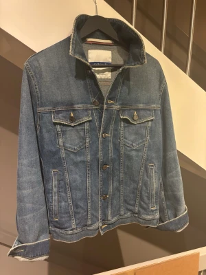Jacob Cohen! - Snygg blå jeansjacka fra Jacob Cohen med raka linjer och två bröstfickor med lock och knapp. Jackan har knappar framtill och detaljerade sömmar som ger en tidlös look. Perfekt att slänga över en hoodie eller t-shirt för en avslappnad stil.