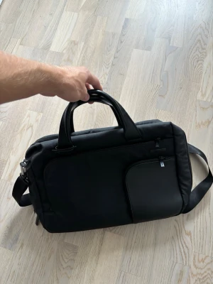 Jättefin svart Samsonite axelremsväska/portfölj - Svart eftertraktad populär och trendig stor rymlig Samsonite axelremsväska (går lika bra att använda som portfölj utan axelbandet). Väldigt praktisk med flera fack för dator mm och i strålande topp skick som ny! I princip helt oanvänd och nypris på flera tusen så väldigt prisvärd! Tveka inte vid minsta fråga eller fundering pris ej hugget i sten