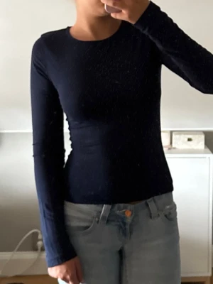 Mörkblå långärmad topp - Snygg mörkblå långärmad topp med rund hals och tight passform. Perfekt att styla med jeans eller kjol för en clean och enkel look. Materialet känns mjukt och stretchigt.