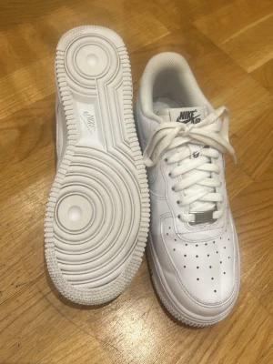 Nike Air Force 1 vita sneakers - Klassiska Nike Air Force 1 sneakers i helvitt läder med vit sula och vita skosnören. Ikonisk design med perforerad tåbox och Nike-logga på sidan. Perfekta för en clean och stilren look. Pris kan diskuteras vid snabb affär! Det är bara att skriva om det är något ni undrar eller om ni vill ha mer bilder💗