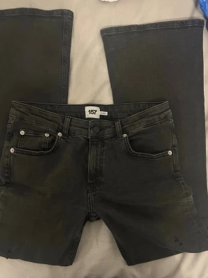 Svarta bootcut jeans med slitningar - Säljer ett par svarta bootcut jeans från 157 med snygga slitningar på ena benet. Jeansen har klassisk femficksmodell, hög midja och vida ben. Materialet är stretchigt denim som sitter skönt och följer kroppen. Modell Low boot, använda ENDAST EN GÅNG!!