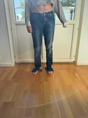 Mörkblå raka jeans med slitningar - Säljer ett par mörkblå jeans med raka ben och lätt slitna detaljer vid bensluten. Jeansen har klassisk femficksmodell, normal midja och knappgylf. Materialet är denim i bomull och passformen är avslappnad och trendig.