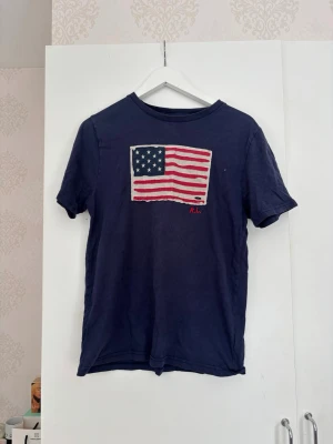Mörkblå t-shirt med amerikansk flagga - Blå Ralph lauren T-shirt. Ser inte storlek men sitter som s/xs.
