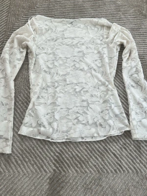 Blommig genomskinlig vit långärmad - Tunn vit genomskinlig tröja med blommor på från ginatricot. Stretchig 