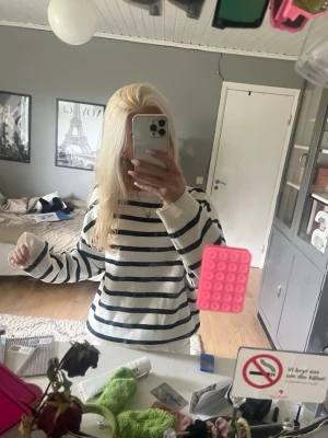 Vit tröja med marinblå ränder - Säljer en vit långärmad tröja med marinblå horisontella ränder. Tröjan har en avslappnad passform, rund halsringning och ribbade muddar vid ärmslut och nederkant. Perfekt för en casual och trendig look.