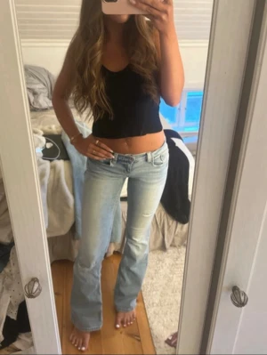 Ljusblå bootcut jeans - Säljer ett par ljusblå bootcut jeans med klassisk femficksmodell och låg midja. Jeansen har en lätt slitning på låret och är tillverkade i denim med en skön passform. Perfekta för en avslappnad och trendig look.