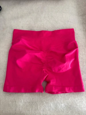 Rosa träningsshorts  - Snygga och bekväma träningsshorts i stark rosa färg. De har en tight passform med ribbad midja och rynkdetalj bak. Perfekta för träning eller en sportig look. Materialet känns mjukt och stretchigt.