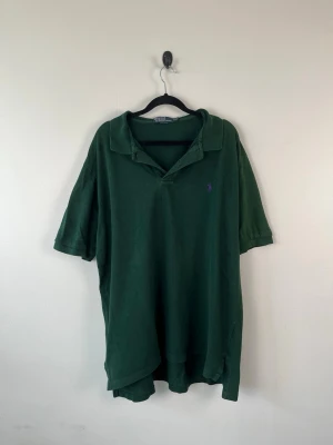 Vintage Polo Ralph Lauren Piké XXL Mörkgrön Oversized Herr Polo Shirt - • Storlek: XXL • Färg: Mörkgrön • Passform: Relaxed Fit  • Krage: Klassisk pikékrage • Material: 100% bomull  Skick: Plagget är i väldigt fint skick med två så mindre hål som syns på bild. Eventuella anmärkningar anges alltid tydligt i beskrivningen och visas på bilderna.  Nypris: Cirka 1 500 kr.  📦 Skickas snabbt och packas omsorgsfullt. 💬 Hör gärna av dig om du har frågor eller vill se fler bilder. 🤝 Samfrakt erbjuds vid köp av flera plagg – kika gärna in mina andra annonser!