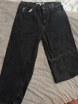 Svarta vida jeans med råa kanter - Säljer ett par svarta big boy polar jeans, löst sittande jeans med bred passform. Jeansen har klassisk femficksdesign och en tvättad vintage-look. Perfekta för en avslappnad och trendig stil. Är i storlek XL men sitter som L.