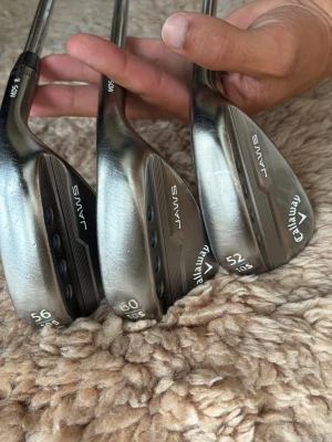 Callaway JAWS golfwedgar 52/56/60° - Säljer tre golfwedgar från Callaway JAWS-serien med loft på 52, 56 och 60 grader. Klubborna är silverfärgade med blå detaljer och har en robust design i metall. Perfekt för dig som vill förbättra ditt närspel på golfbanan.