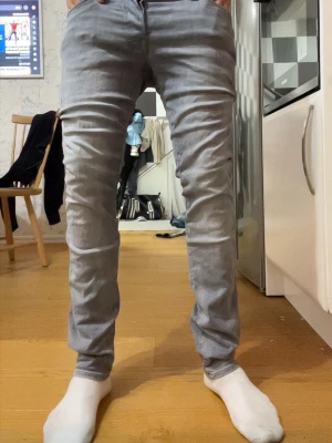 Ljusgrå jack & jones  slim fit jeans - Säljer ett par ljusgrå slim fit jeans med klassisk femficksdesign och raka ben. Jeansen har en enkel look utan slitningar och är tillverkade i ett mjukt denimtyg som passar perfekt till en avslappnad stil.