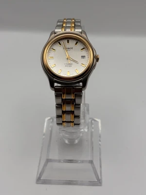 Tissot PR 50 titan klocka silver/guld - Stilren Tissot PR 50 klocka i titan med silverfärgad urtavla och datumvisning. Armbandet är i titan med guldfärgade detaljer och klassisk länkdesign. Perfekt accessoar för dig som gillar en tidlös look.