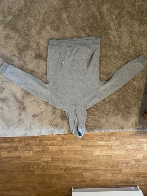 Grå basic hoodie med huva - En enkel och stilren grå hoodie med huva och långa ärmar. Hoodien har en klassisk känguruficka framtill och ribbade muddar vid ärmslut och nederkant. Perfekt för en chill och avslappnad look. Materialet känns mjukt och bekvämt.