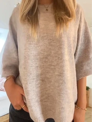 Beige oversized stickad tröja - Mysig beige stickad tröja i oversized modell med halvlånga ärmar och rund halsringning. Tröjan har en mjuk och fluffig känsla, perfekt för lager på lager. Passar till jeans eller kjol för en avslappnad look.