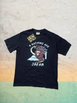 Svart Bape t-shirt - Riktigt snygg svart T-shirt från Bape i storlek M, med snyggt tryck framtill. Skön passform och sitter riktigt bra på. En riktigt fet piece som ger starka archive/vintage-vibbar.