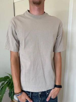 Beige basic t-shirt i bomull - En stilren beige t-shirt i mjuk bomull med normal passform och korta ärmar. Perfekt till jeans eller shorts för en enkel och clean look. Klassisk rund halsringning och utan tryck eller mönster.