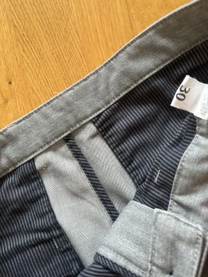 Grå kostymbyxor från Zara - Snygga grå kostymbyxor från Zara med klassisk passform. Byxorna har diskreta ränder på insidan av linningen och är tillverkade i ett mjukt, vävt material som ger en stilren look. Perfekta för dig som vill ha en clean och modern stil. 