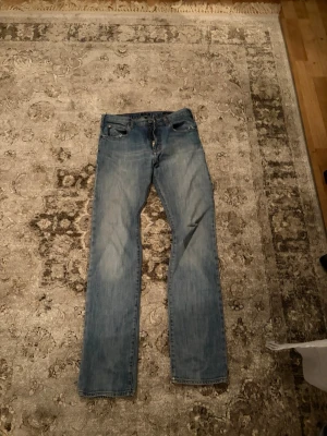 Ljusblå emporio armani raka jeans - Säljer ett par ljusblå jeans med rak passform och klassisk femficksdesign. Jeansen har en snygg tvättad look och är tillverkade i denim. Perfekta för en avslappnad stil och passar till det mesta i garderoben.