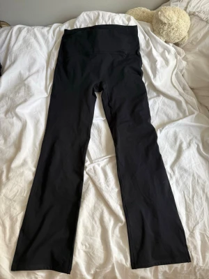 Svarta bootcut leggings - Säljer ett par svarta leggings med bootcut-modell och hög midja. De är stretchiga och sitter skönt på kroppen, perfekta till en avslappnad look. Materialet känns mjukt och följsamt.