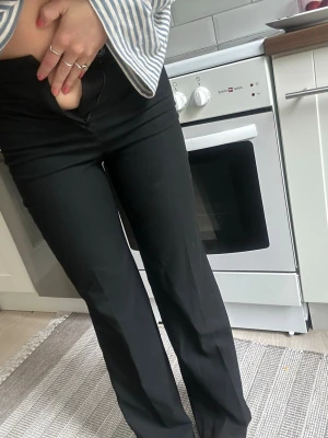 Svarta raka kostymbyxor - Säljer ett par svarta kostymbyxor med rak passform och hög midja. Byxorna har diskreta fickor och stängs med dragkedja och knapp. Perfekta till en stilren look och passar till många olika outfits.