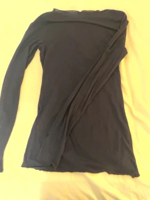 Svart långärmad topp - En enkel och stilren svart långärmad topp i tunnare material. Toppen har en klassisk passform och är perfekt att styla med jeans eller kjol. Materialet känns mjukt och följsamt mot huden. Den har tyvärr fått några hål vid ärmarna och därför säljer jag för lite billigare. Skriv om det är några funderingar.