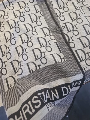 Gråsvart poncho - Snygg ponchol i grått och svart med ikoniskt logomönster längs kanten. Tunt, vävt material som känns lyxigt och passar perfekt till att lyfta vilken outfit som helst.