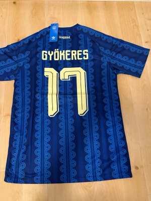 Gyökeres #17 – Sverige Borta (storlek S) - Gyökeres #17-tryck. Sverige Borta (blå). Storlek S. Helt ny och aldrig använd. Skickas snabbt 🚚💨  Mått (S): Halvt bröstmått 51 cm • Längd 72 cm • Ärmbredd 22 cm • Axelbredd 42 cm • Ärmlängd 39 cm • Manschett 18 cm.  🔥 Fan Edition – normal passform. 🇸🇪 Sverige landslag.  📩 Frågor eller prisförslag? Skicka gärna ett meddelande! 🛍 Bundle-rabatt upp till 20% 💰 📦 Skickas samma eller nästa dag 🌟