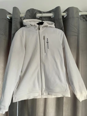 Vit hoodie från Sail Racing - En fin zip hoodie från Sail racing, tröjan är använd ungefär 10 gånger och är i nyskick. Den är i stlk 176 och sitter som S/M