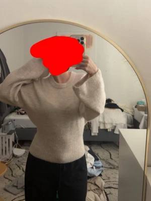 Beige stickad tröja med ballongärm - Mysig beige stickad tröja med rund halsringning och bred ribbstickad midja. Tröjan har långa ballongärmar som ger en avslappnad och trendig look. Perfekt att matcha med både jeans och kjol för en chill outfit.