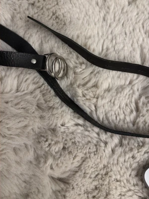 Svart bälte med dubbla ringar - Snyggt svart bälte i skinnimitation med dubbla silverfärgade ringar som spänne. Perfekt accessoar för att lyfta vilken outfit som helst. Bältet har en stilren och minimalistisk design.