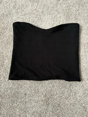 Svart ribbad bandeau tubtopp - Tubbtopp, använd ett fåtal gånger men inget som syns. Perfekt att styla med ett par kostymbyxor elelr vita jeans!!! 