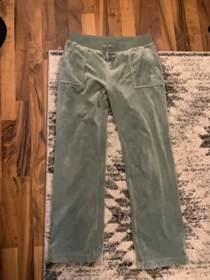 Gröna velour mjukisbyxor med fickor - Snygga ljusgröna mjukisbyxor i mjuk velour med bred resår i midjan och dragsko. Byxorna har stora framfickor och bakfickor med knappdetaljer. Perfekta för chill dagar och har en relaxed passform.