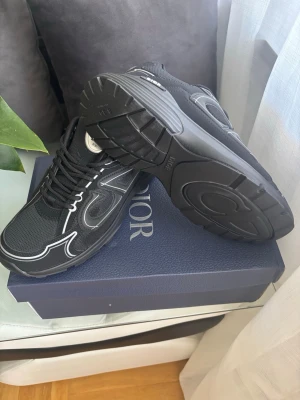 Svarta sneakers med vita detaljer - Snygga svarta sneakers  med vita kontrastdetaljer och meshpaneler. Skorna har en chunky sula och klassisk snörning. Perfekta för dig som vill ha en stilren men ändå unik look. Kommer i originalkartong.