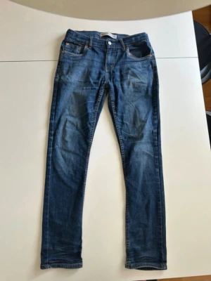 Levi’s Jeans - Snygga blå slim fit jeans med klassisk femficksdesign och normalhög midja. Jeansen har en lätt tvättad look med subtila slitningar och raka ben. Tillverkade i denim med en skön passform som funkar till det mesta. Perfekta för dig som gillar en enkel och stilren stil. Modellen är 512 Slim Taper. Hör av dig om du har några frågor!