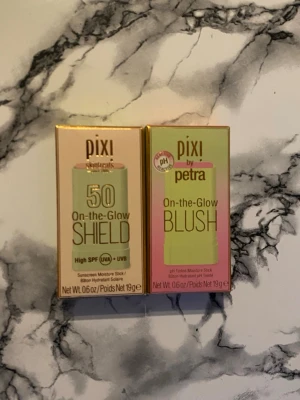 Pixi On-the-Glow Shield & Blush - Säljer två produkter från Pixi: On-the-Glow Shield med SPF 50 för solskydd och On-the-Glow Blush som ger färg till kinderna. Båda kommer i smidiga stiftformat och har fräscha pastellfärger på förpackningen. Perfekt att ha med i väskan för snabb touch-up.