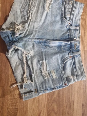 Ljusa denimshorts med slitningar - Säljer ett par ljusblå denimshorts med en pussmun på ena bakfikan, i fint skick lch väldigt snygga.    #baggyjeans #lowwaist jeans #cargobyxor #vida jeans #flarejeans #lågmidja #rakajeans #kostymbyxor #mjukisbyxor #oversizedhoodie #ziphoodie #stickadtröja #corsettopp #offshoulder #babytee #linne med spets #oversized tshirt #stickadväst #maxikjol #y2k #vintage #streetwear #oldmoney #cleangirl #basic #festkläder #vardagskläder #unisex #oversized #fitted #cozy #retro #zara #hm #bikbok #ginatricot #