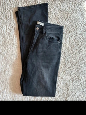 Svarta bootcutjeans m. medelhög midja - Säljer ett par svarta jeans med bootcut passform. Jeansen har medelhög midja och är tillverkade i ett mjukt denimtyg som ger en snygg och stilren look. Perfekta till alla outfits.